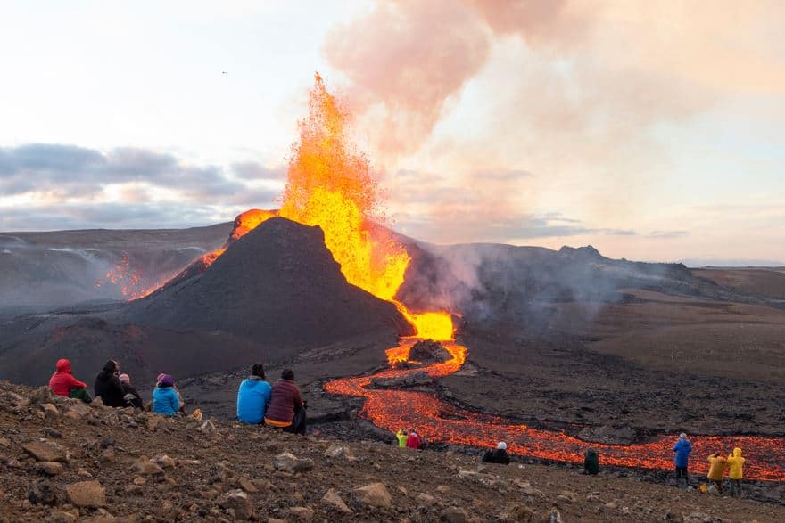 An image of a real volcanic eruption, with some people watching it.